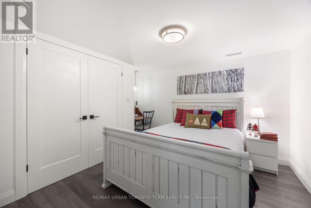 Basement bedroom staged with plaid quilt and handcrafted cushions.
