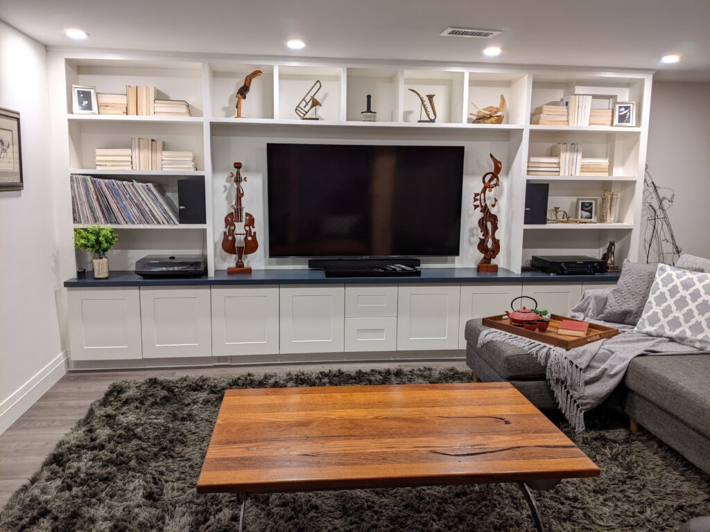 Bookshelf styled with neutral books and wood instrument sculptures.