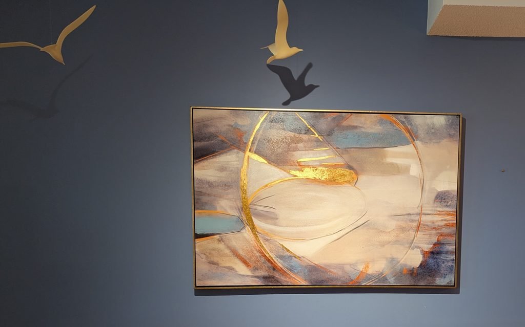 Artwork with pot light aimed to show it off as well as brighten the dark wall.